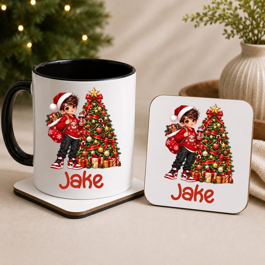 A white ceramic mug with a black handle and interior, printed with a Christmas child in a Santa hat next to a decorated tree and the name 'Jake' in red, shown on a coaster beside a matching square coaster.