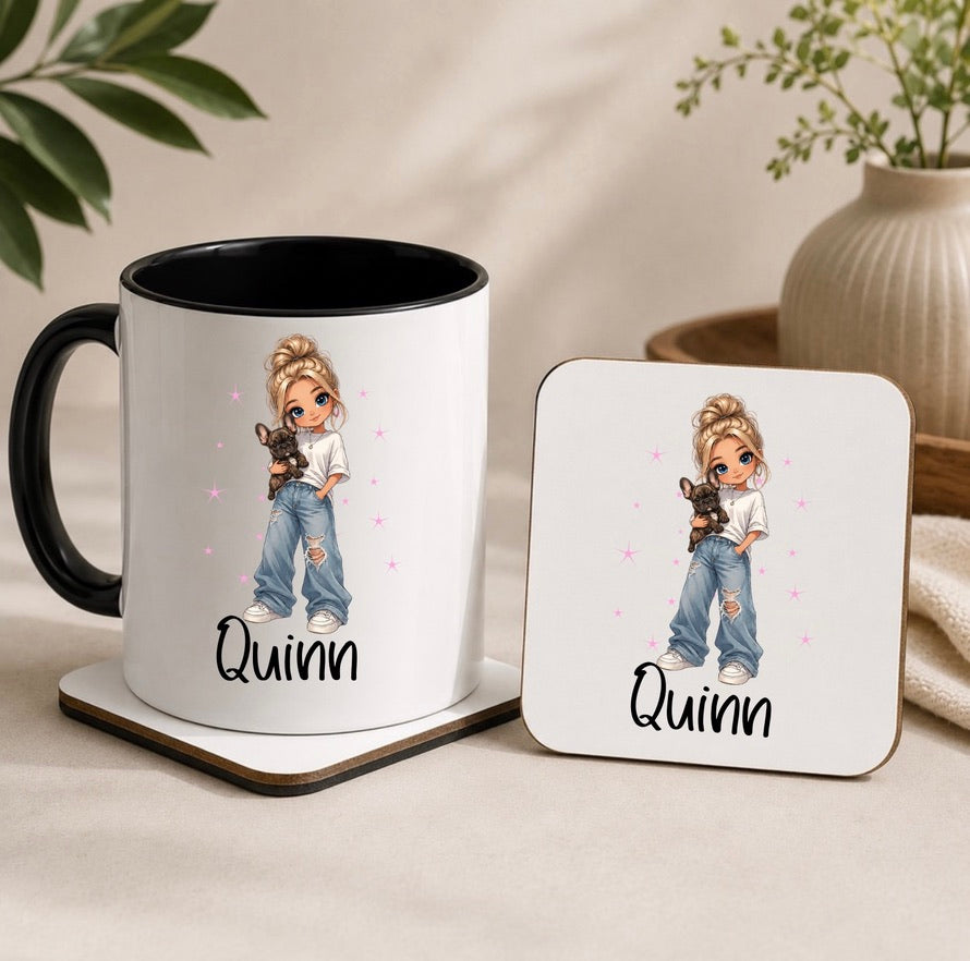 A white ceramic mug with a black handle and interior, alongside a matching square coaster, both printed with a cartoon girl holding a small black cat and the name 'Quinn' in black script. The mug and coaster sit on a beige tabletop with soft-focus decorative plants and a vase in the background.
