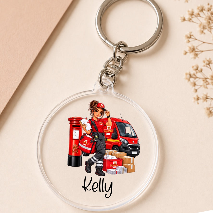 A personalized acrylic keychain featuring an illustration of a female postal worker in red next to a red post box, van, and packages, with the name 'Kelly' printed below. The keychain is shown on a beige background with a kraft paper corner and dried flowers.