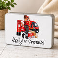 A rectangular metal tin with rounded corners, featuring a custom illustration of a postman in a red uniform next to a red post box, van, and packages, with the text 'Kelly's Snacks' written in black script. The tin is shown on a light wooden tabletop with a neutral background.