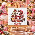 Personalised snowman Christmas ceramic tile with custom name, featuring a festive snowman, Christmas tree and presents displayed on a wooden stand.